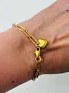 Gold-tone link chain bracelet with polished heart charm, displayed on a model.