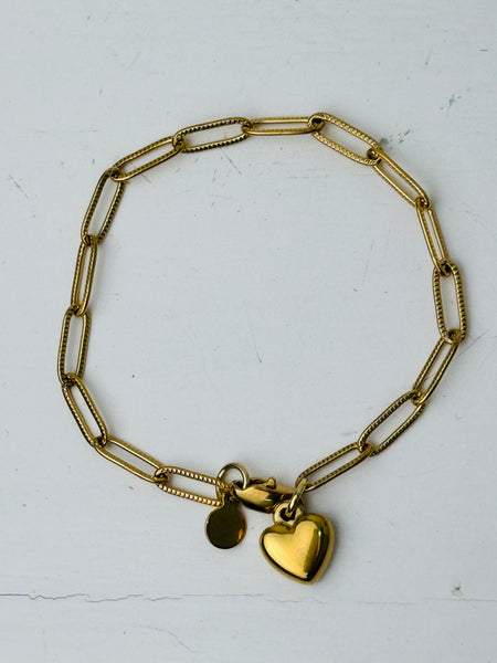 Gold-tone link chain bracelet with polished heart charm, displayed on a white background.