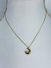 Gold necklace with a crescent moon pendant on a mannequin.