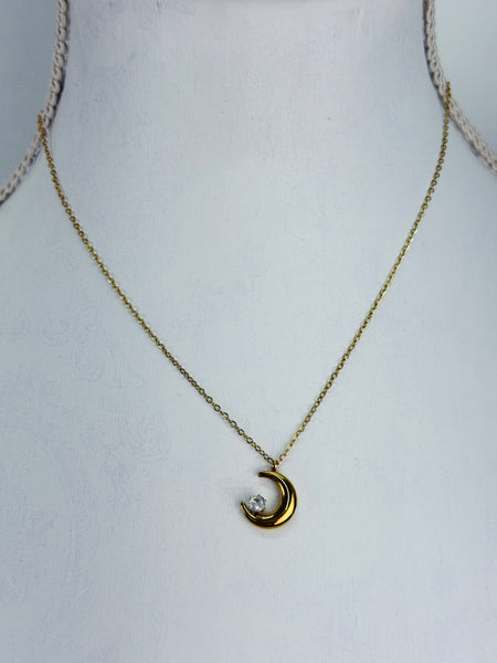 Gold necklace with a crescent moon pendant on a mannequin.