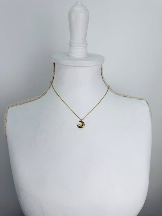 Gold necklace with a moon and star pendant on a mannequin 