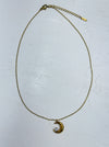 Gold necklace with a crescent moon pendant with crystal star detail on a white background