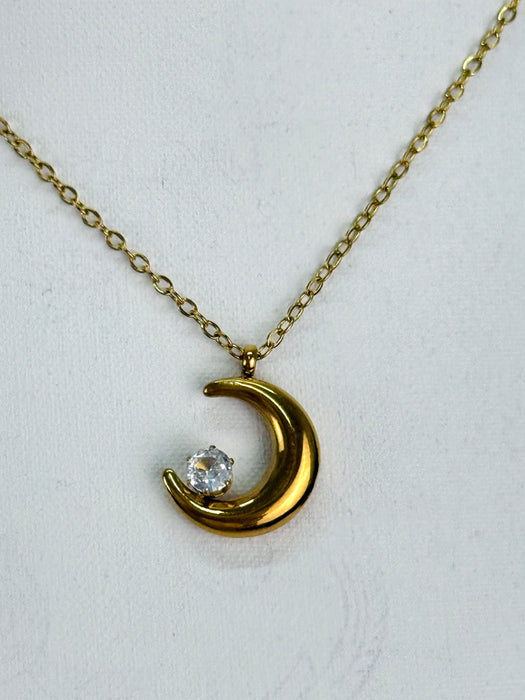 Gold crescent moon necklace with a diamond on a white background