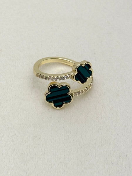 Gold ring with green clover-shaped stones on a white background