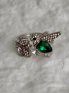 Silver ring with green gemstone on a gray textured background
