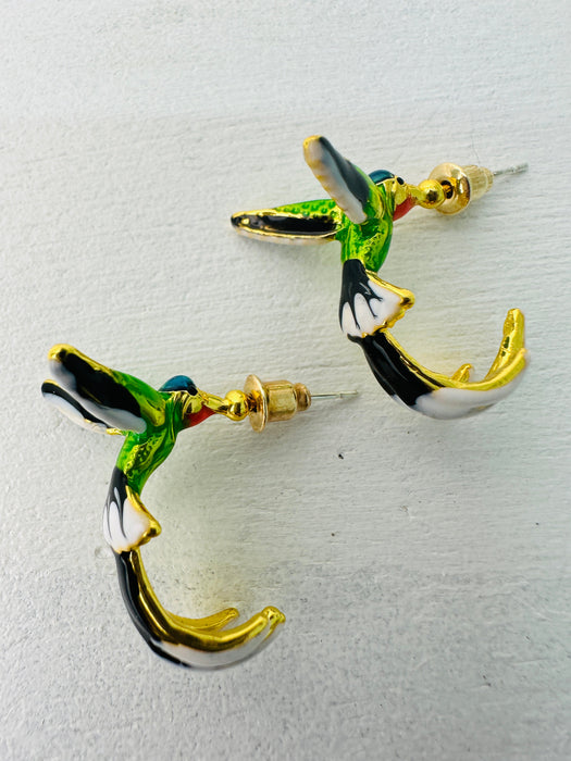 Hummingbird-shaped earrings with gold accents on a light gray background