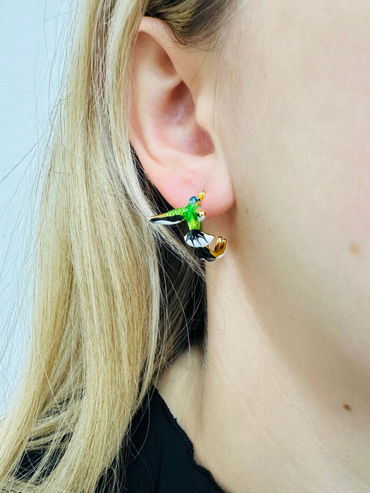 Close-up of a person wearing a colorful bird-shaped earring.