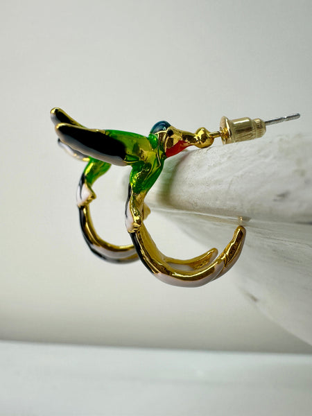 A pair of hummingbird-shaped earrings with green and gold colors on a white surface.