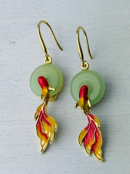 A pair of earrings featuring a gold-colored design with a green jade-style ring and a red and yellow koi fish motif.