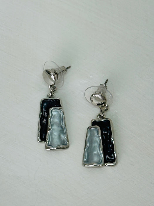 Grey and gunmetal rectangular enamel drop earrings with silver-tone outline, displayed on a table.