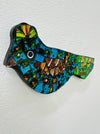 A hand painted glass mosaic in the shape of a blue and green bird with gold accents.