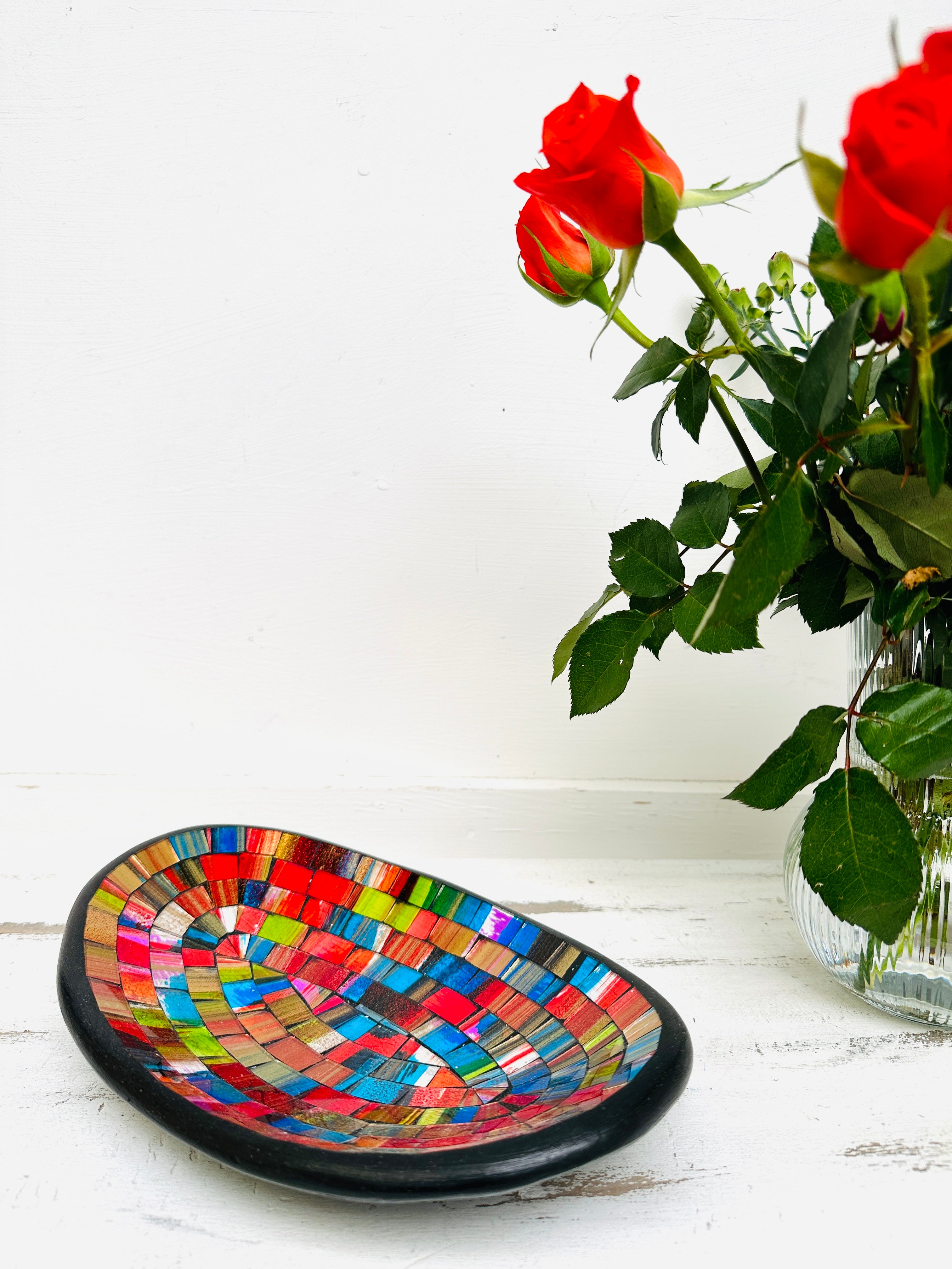 display view of mosaic oval bowl next to a vase of flowers