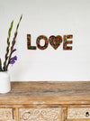 display view of LOVE attached on wall with vase of flowers