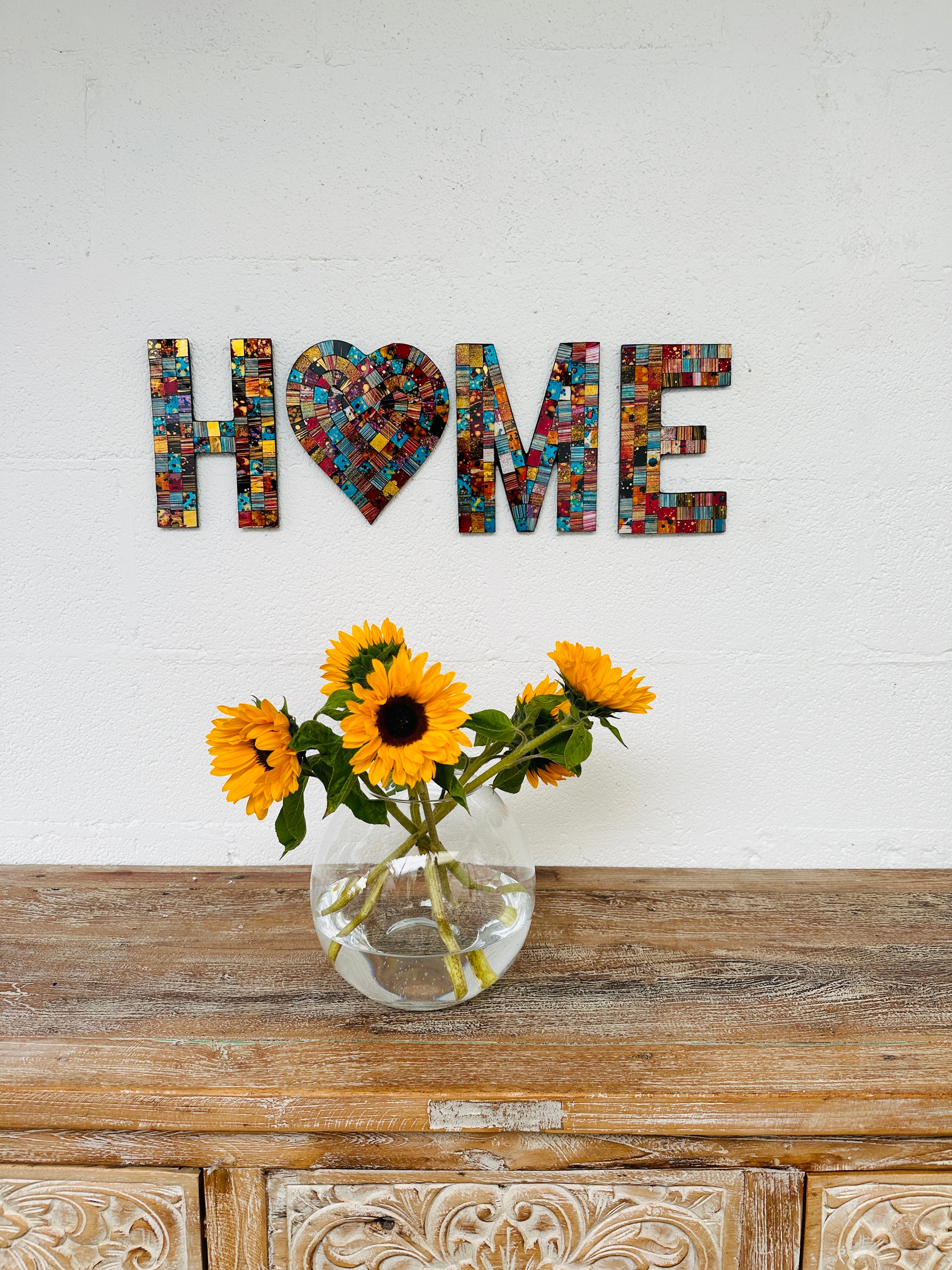 display view of mosaic home with vase of flowers below