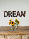 display view of DREAM mosaic wall art with a vase of flowers on the table below