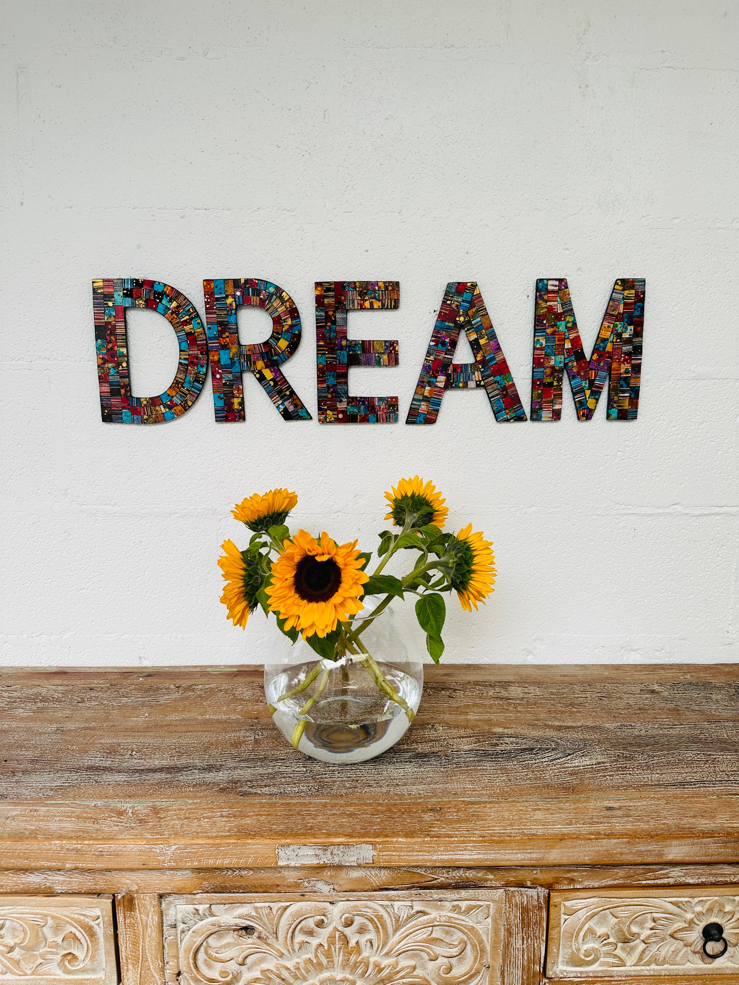 display view of DREAM mosaic wall art with a vase of flowers on the table below