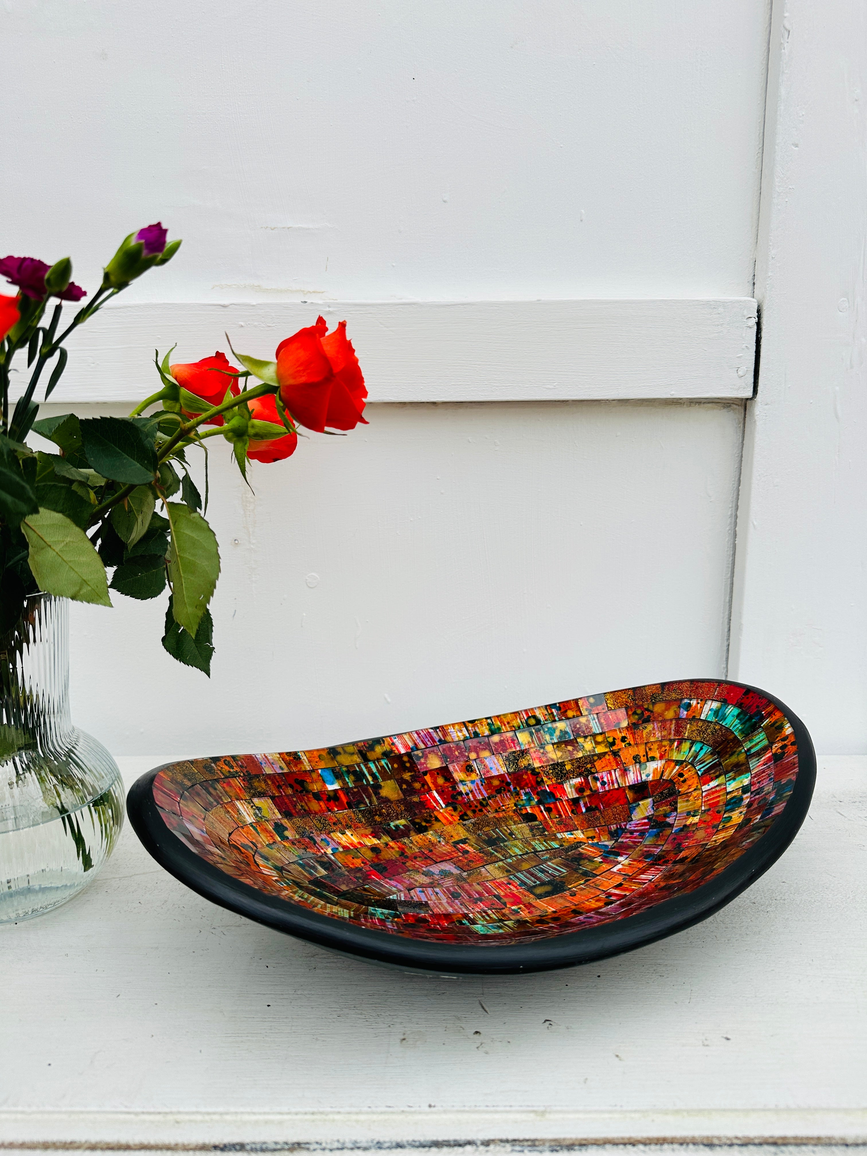 display view of mosaic oval bowl next to a vase of roses