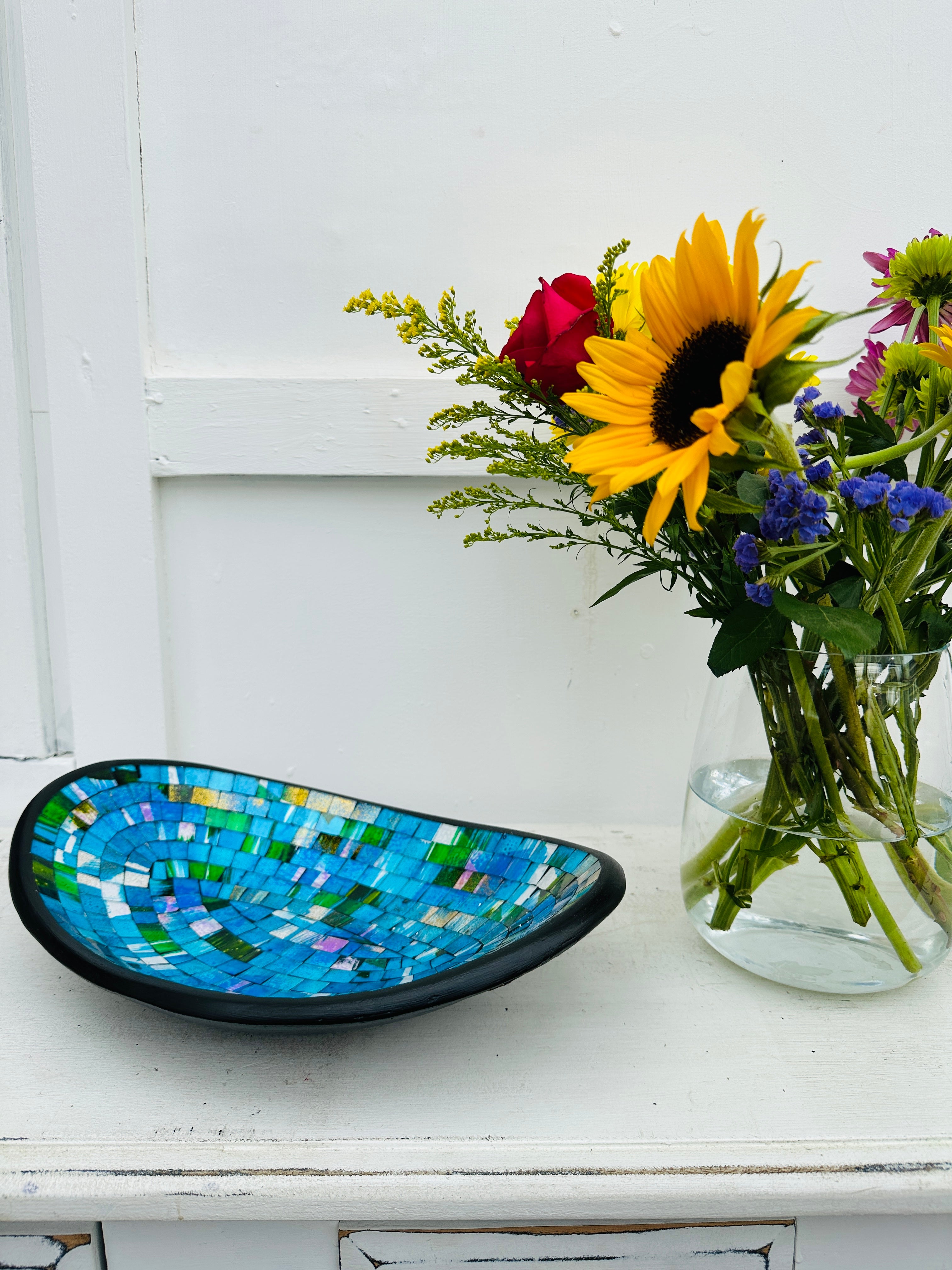 display view of mosaic oval bowl next to a vase of flowers