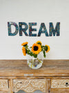 display view of mosaic DREAM above a vase of flowers on a wooden dresser.