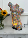 display view of mosaic man body lamp with light on next to a vase of flowers