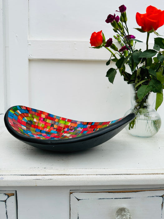 side view of mosaic oval bowl next to a vase of roses