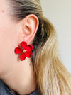 front view of matte red flower-shaped earring worn by a person 