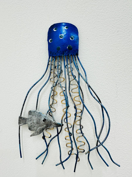 A blue metal jellyfish wall art with coiled tentacles and a small fish attached.