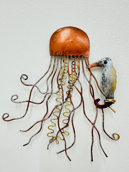 A copper-toned metal sculpture of a jellyfish with a small seahorse attached, both hand-painted with a unique finish.