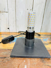 Lamp base and bulb fitting with black cable, inline switch and UK plug on wooden table, showing epoxy resin base.