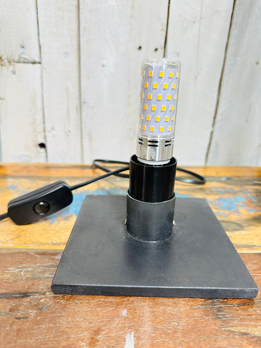 Lamp base and bulb fitting with black cable, inline switch and UK plug on wooden table, showing epoxy resin base.