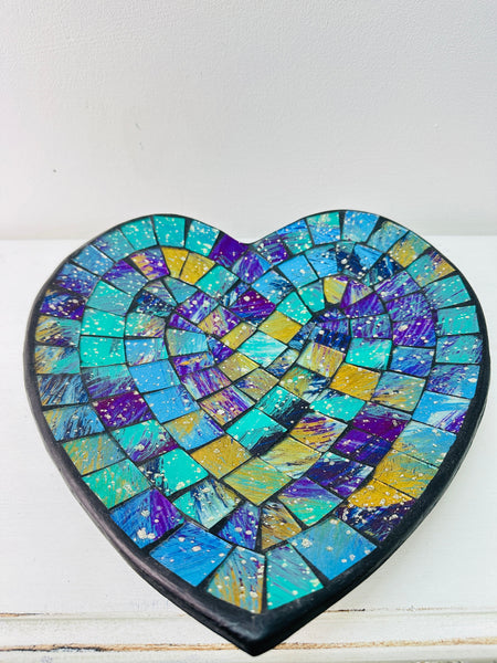 Top view of handmade mosaic heart bowl in blue, green and turquoise glass pieces on white background.