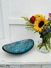 display view of mosaic oval bowl next to a vase of flowers