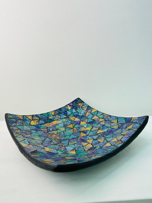 Angled view of handmade mosaic square plate showing terracotta base and glossy cyan glass surface on white background.