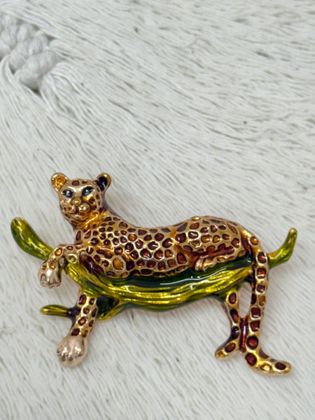 Gold-tone leopard brooch with enamel spots an a branch.
