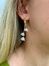 A pair of elegant dangle earrings with white floral designs and gold stems.