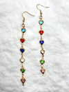Long earrings with heart-shaped gemstones on a textured white background