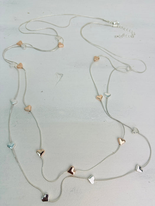 close-up of a long double-chain mixed metal heart charm necklace with a silver and gold hearts 