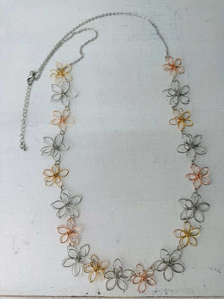 Necklace with floral designs in silver, gold, and rose gold on a white background