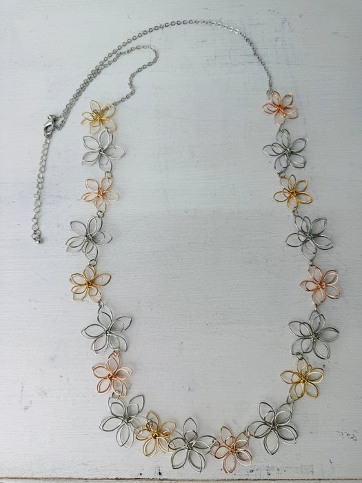 Necklace with floral designs in silver, gold, and rose gold on a white background
