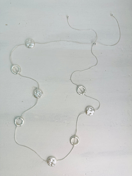 front of long silver chain station necklace with acrylic faux-shell circles 