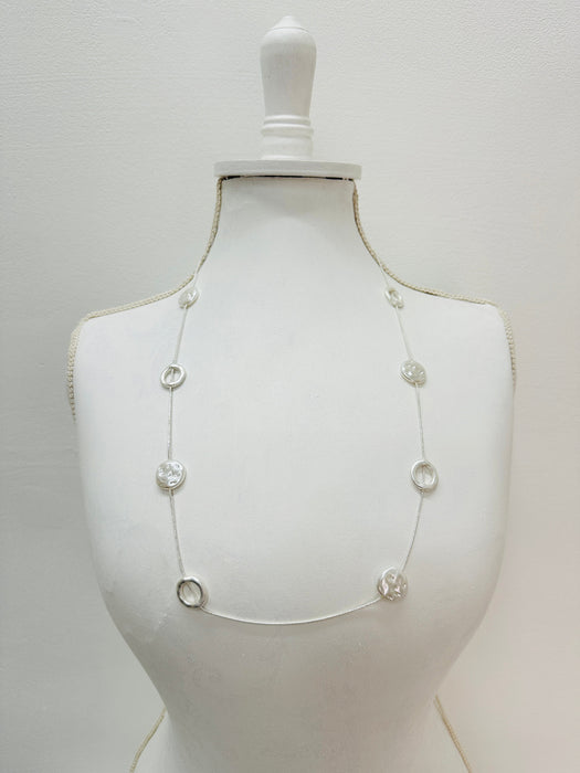 Long silver chain station necklace with acrylic faux-shell circles displayed on a mannequin
