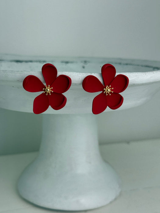 close-up of matte red flower-shaped earrings on a white background