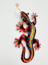 A colorful metal gecko with red, yellow, blue, and pink patterns on a white background.