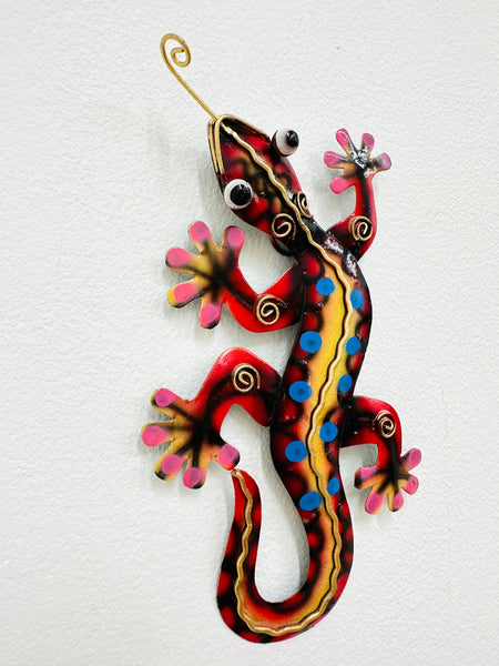 A colorful metal gecko with red, yellow, blue, and pink patterns on a white background.