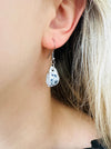 close - up of of mini porcelain tea cup drop earring with floral design on a model