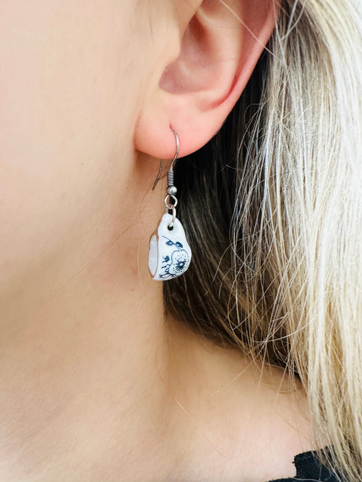 close - up of of mini porcelain tea cup drop earring with floral design on a model