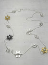 mixed metal necklace with flower motifs pearl details and shell accents on a light gray background