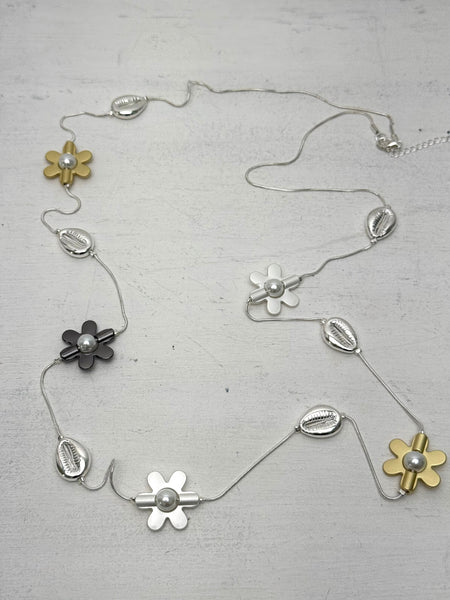 mixed metal necklace with flower motifs pearl details and shell accents on a light gray background