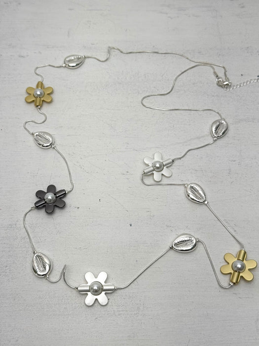 mixed metal necklace with flower motifs pearl details and shell accents on a light gray background