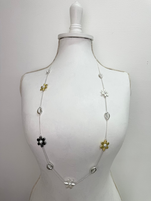mixed metal necklace with flower motifs pearl details and shell accents on a mannequin against a white background